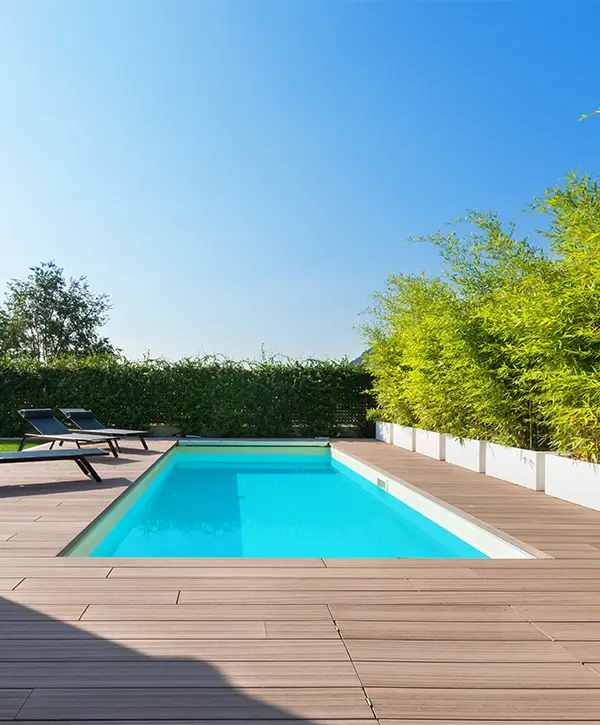 A deck around a pool with long chairs