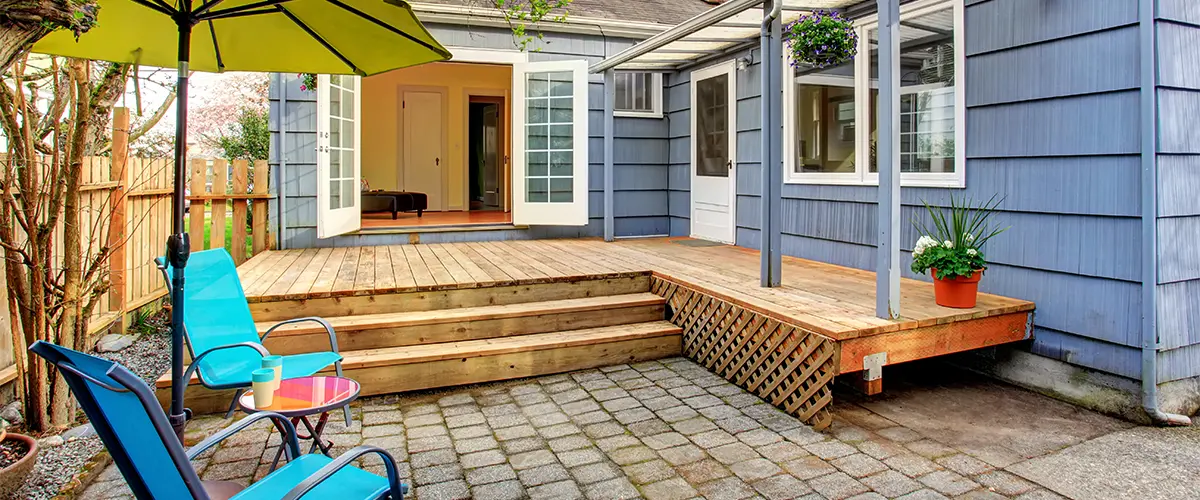 A small deck in the backyard of a home with blue siding