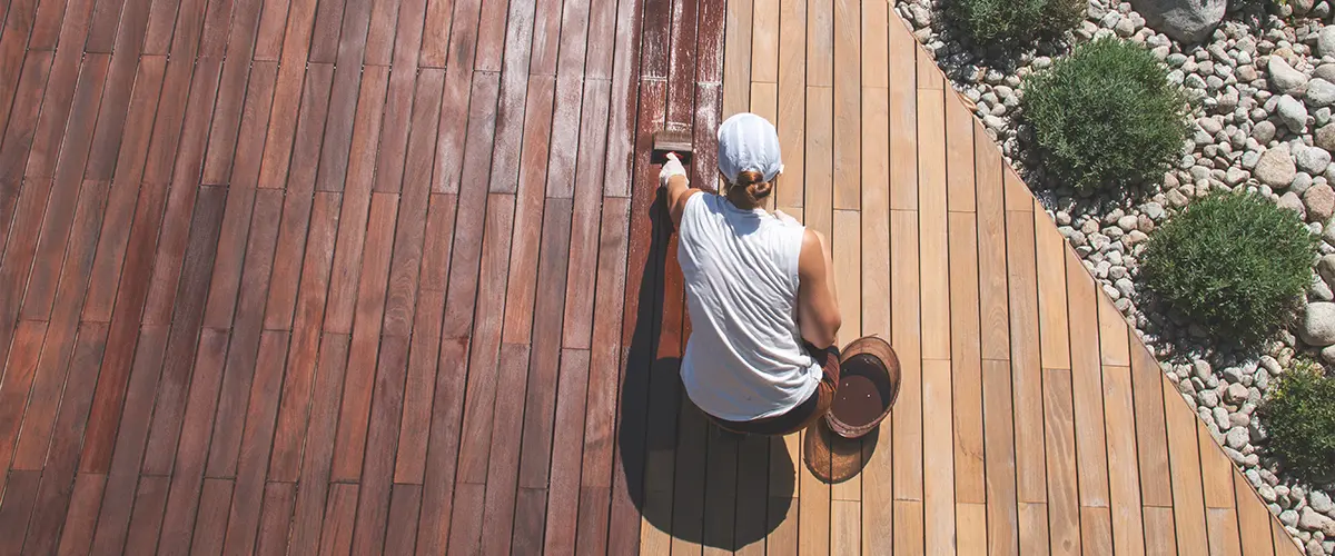 Woman staining a wooden deck