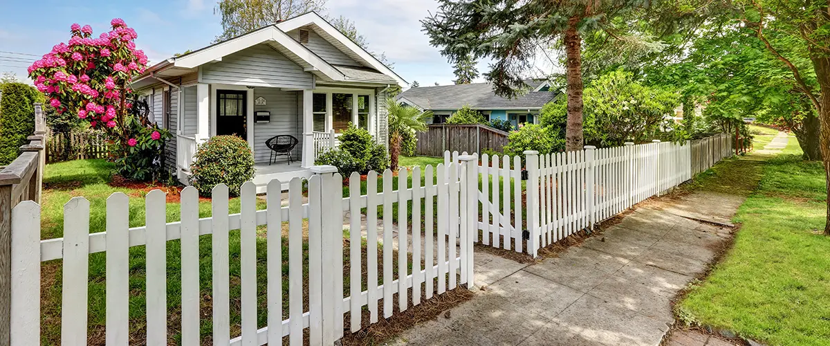 Picket vinyl fence with small home and lawn