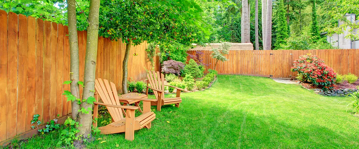A cedar fence on a large lawn with furniture