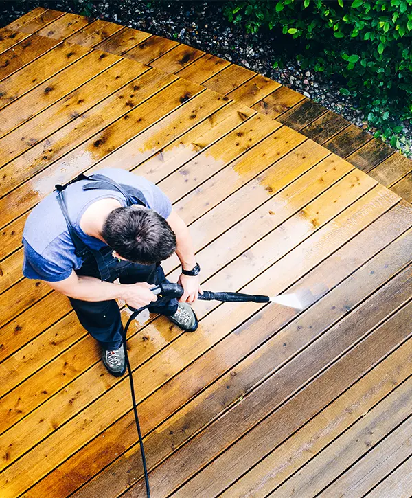 A contractor pressure washing a deck