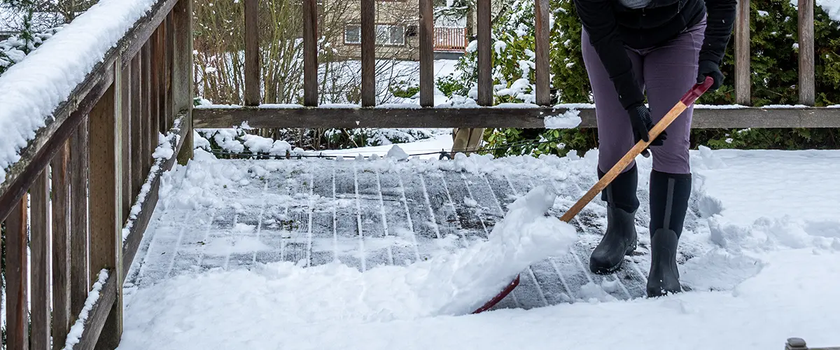 A woman preparing a deck for winter by shoveling it