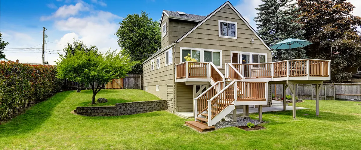 A home on a large lawn with a second-story wooden deck