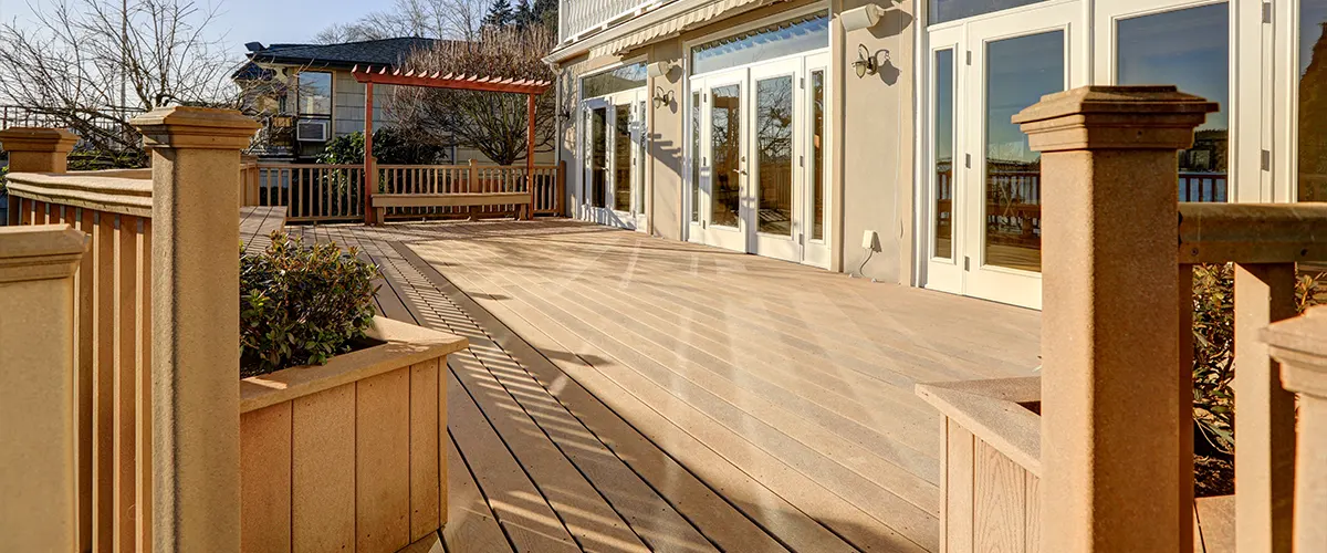 Composite decking and railing on a beige outdoor space attached to a home