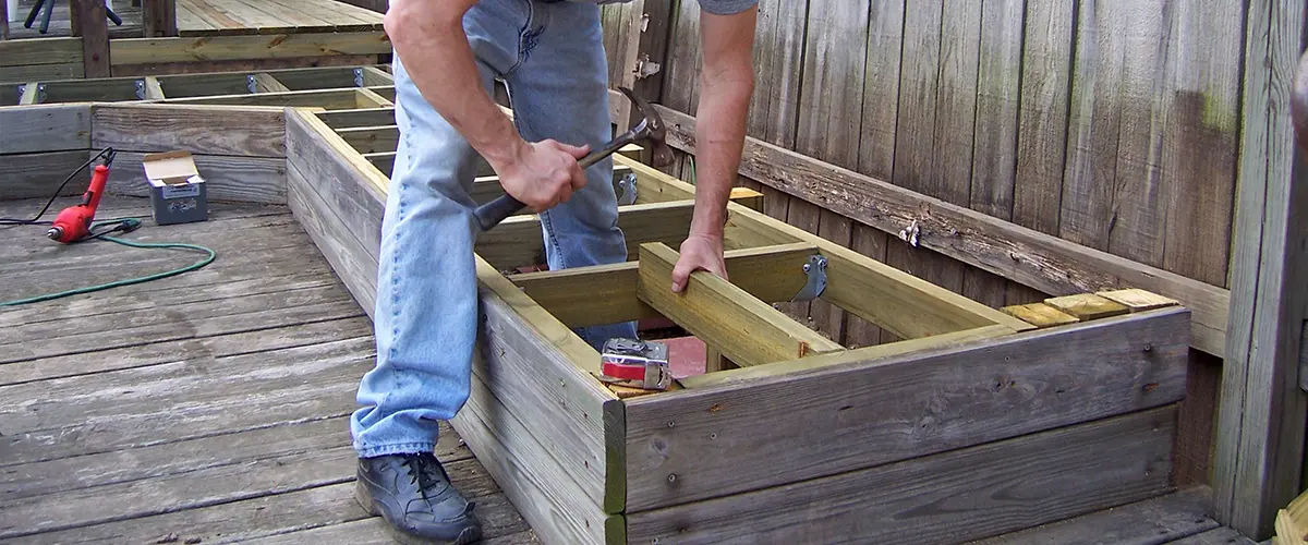 A contractor restoring a decking surface and building a bench