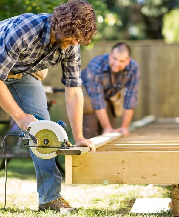 The Best Deck Building In Alderwood Manor, WA Carpenter Cutting Wood With Handheld Saw While Coworker Helping