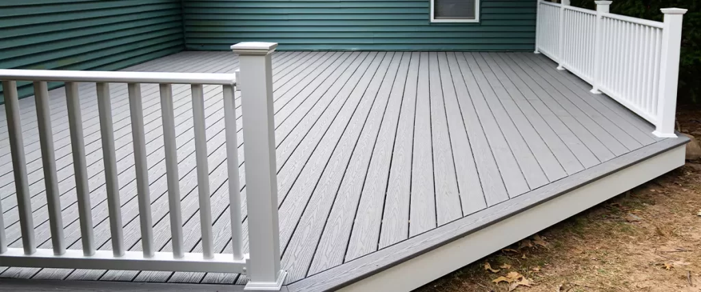 timbertech vs trex decking. New composite deck on the back of a house with green vinyl siding.